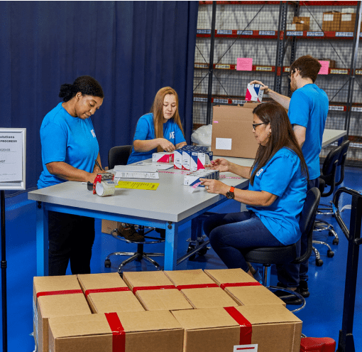 Four diverse employees work together to package products.